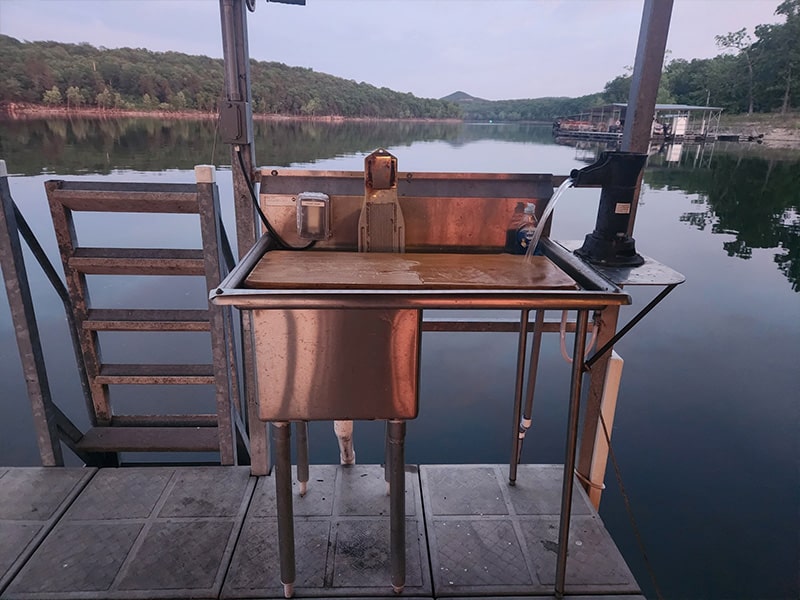 FISH CLEANING STATION Stainless steel fish sink with running water and cutting board.